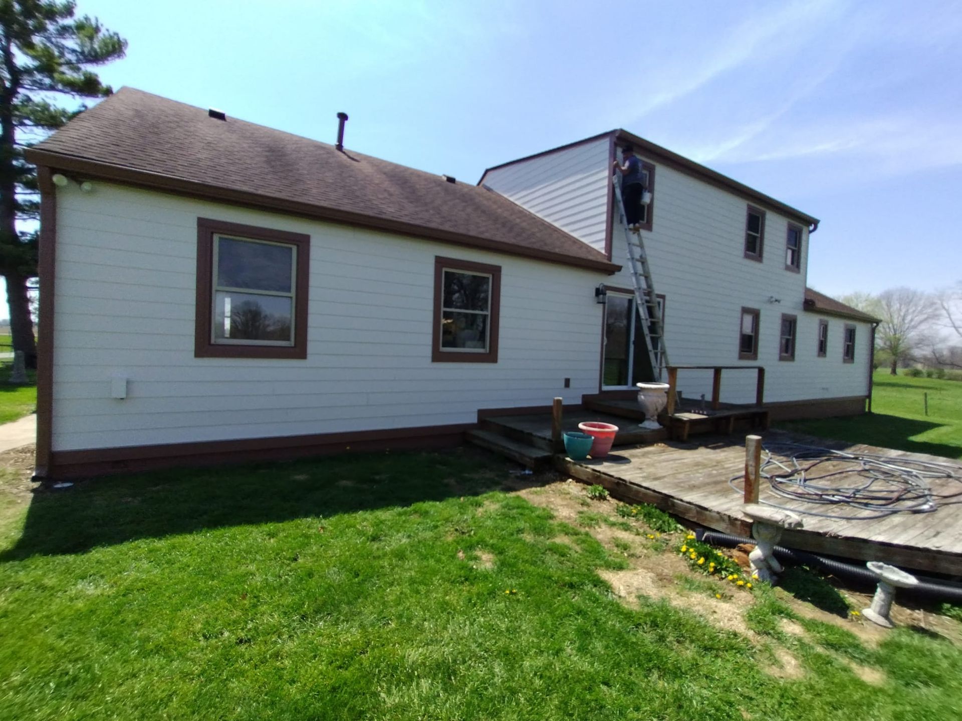 A white house with a brown roof is sitting on top of a lush green field.
