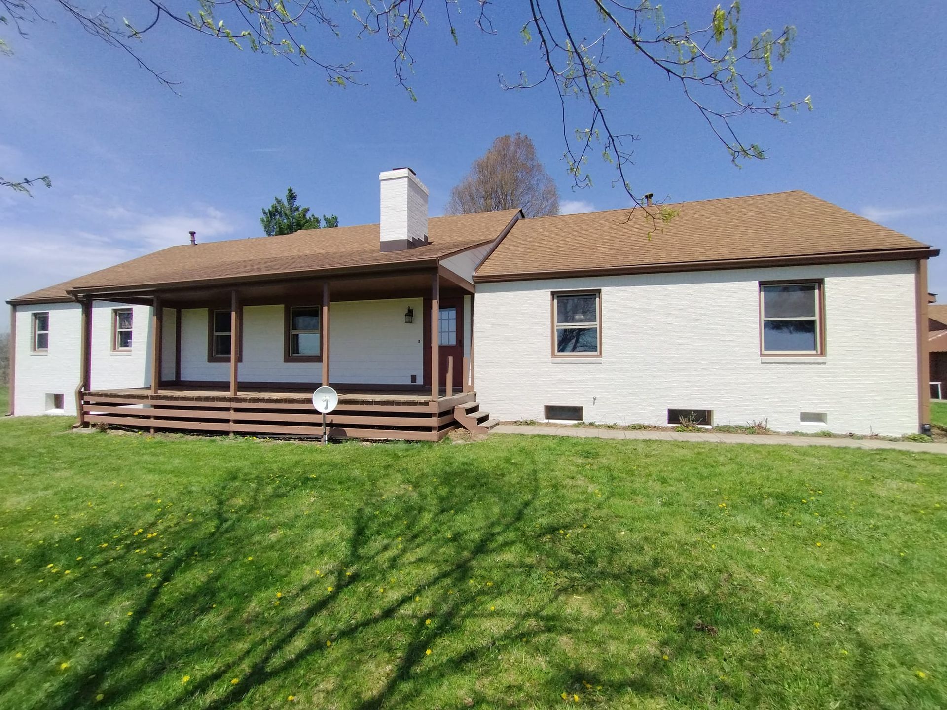 A white house with a brown roof and a porch