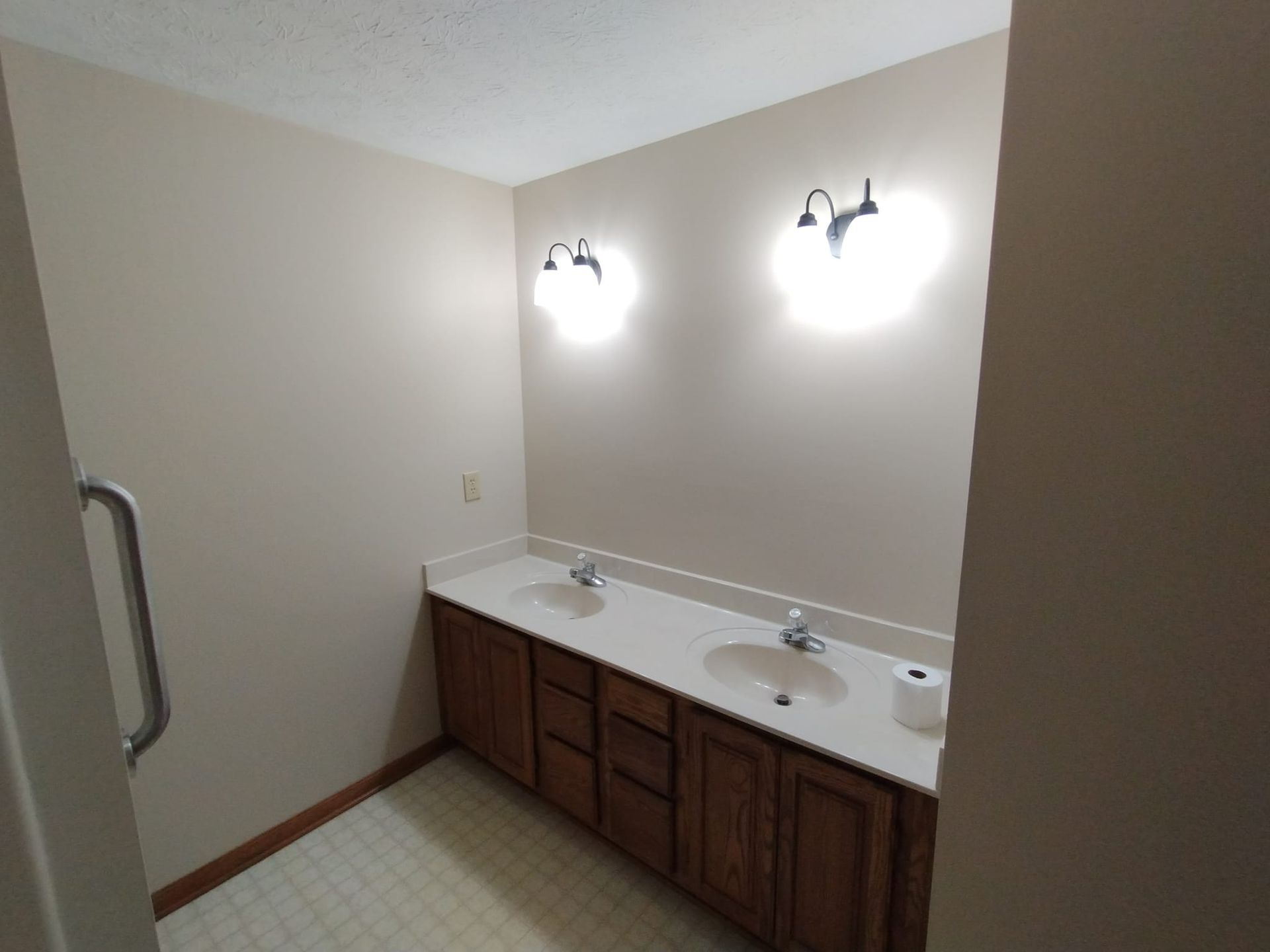 A bathroom with two sinks and two lights on the walls