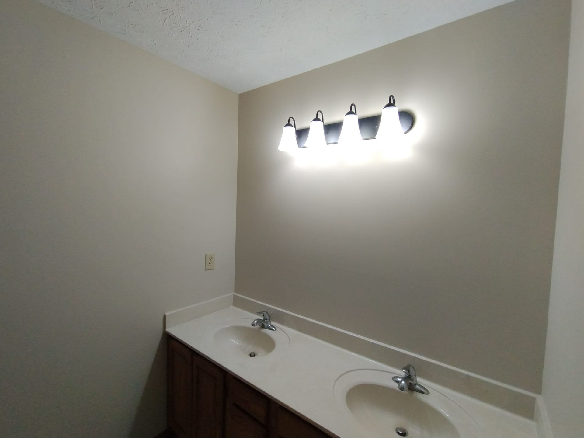 A bathroom with two sinks and a light on the wall