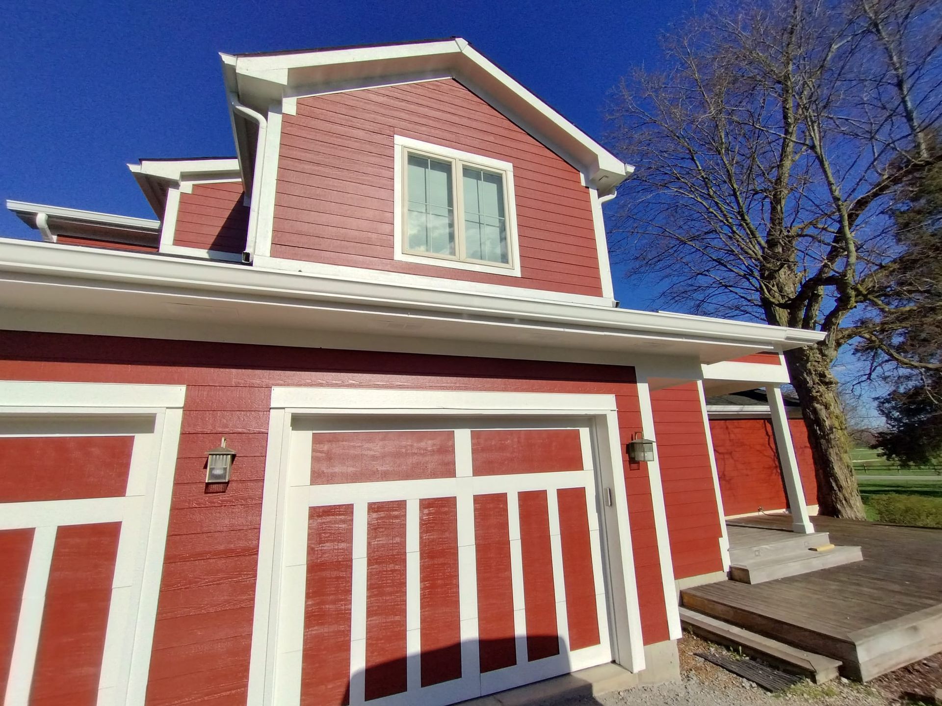 A red house with a white trim and a garage door