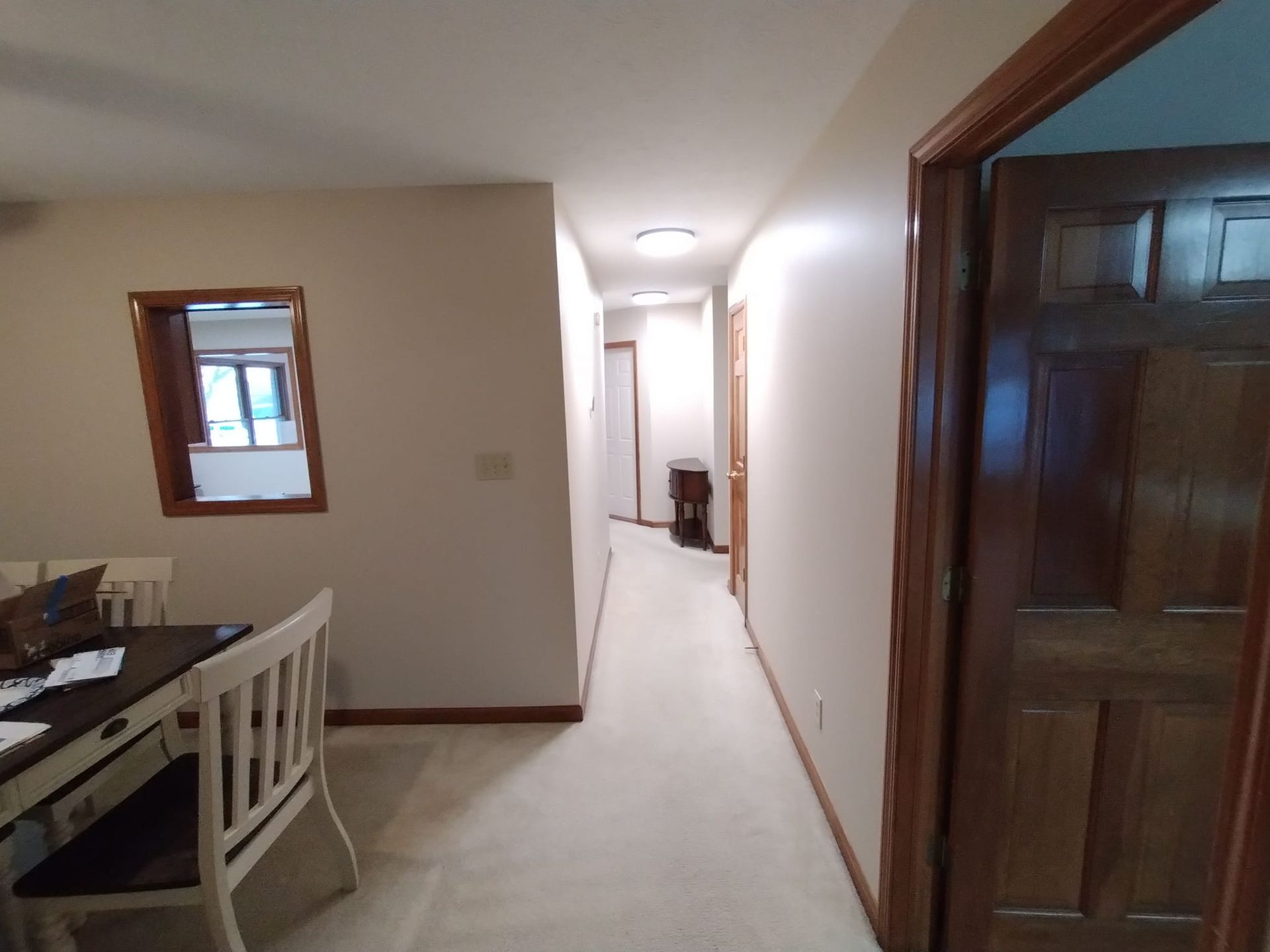 A long hallway leading to a dining room with a table and chairs