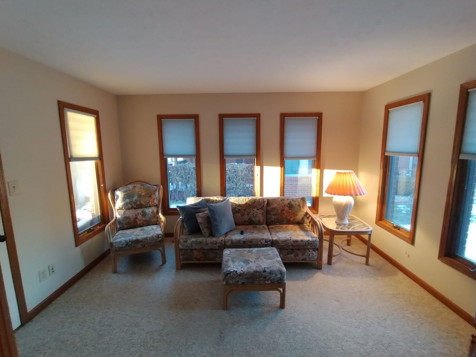 A living room with a couch , chairs , ottoman and a lamp.