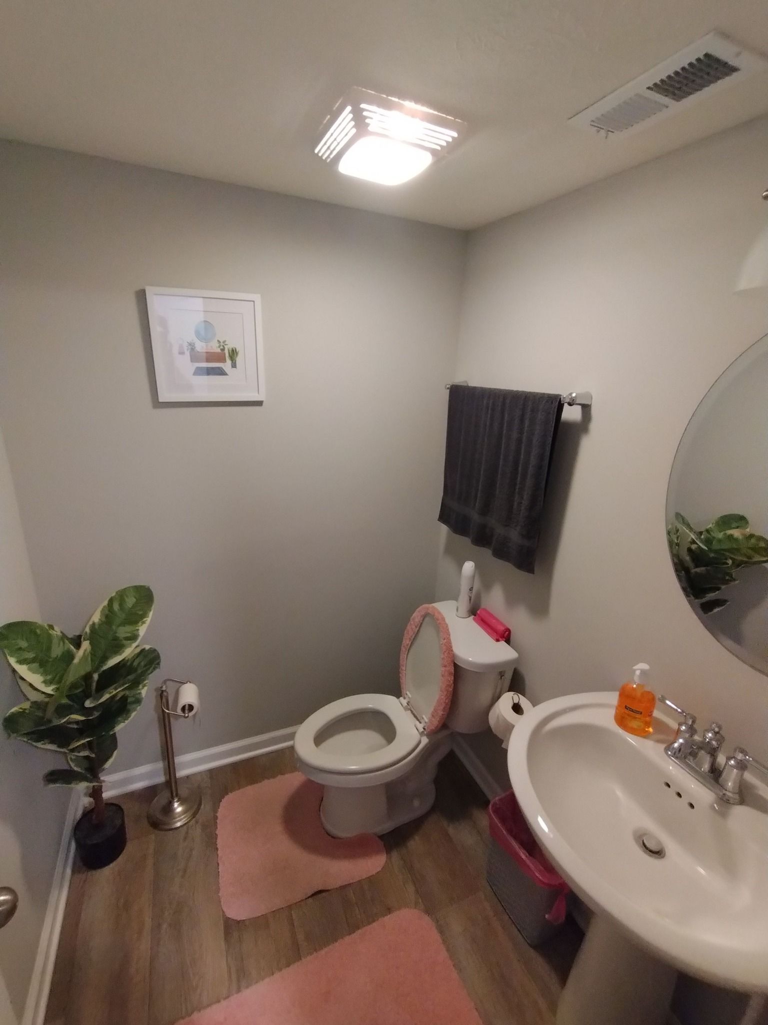 A bathroom with a toilet , sink and mirror.