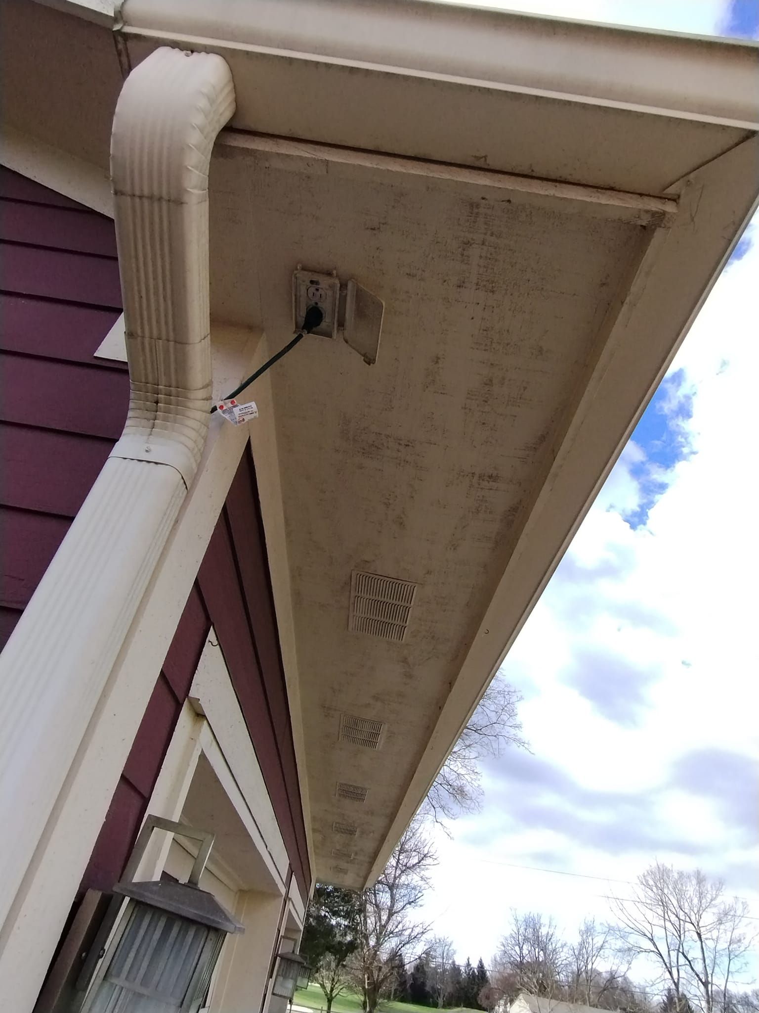 The roof of a house has a drain pipe and a light on it