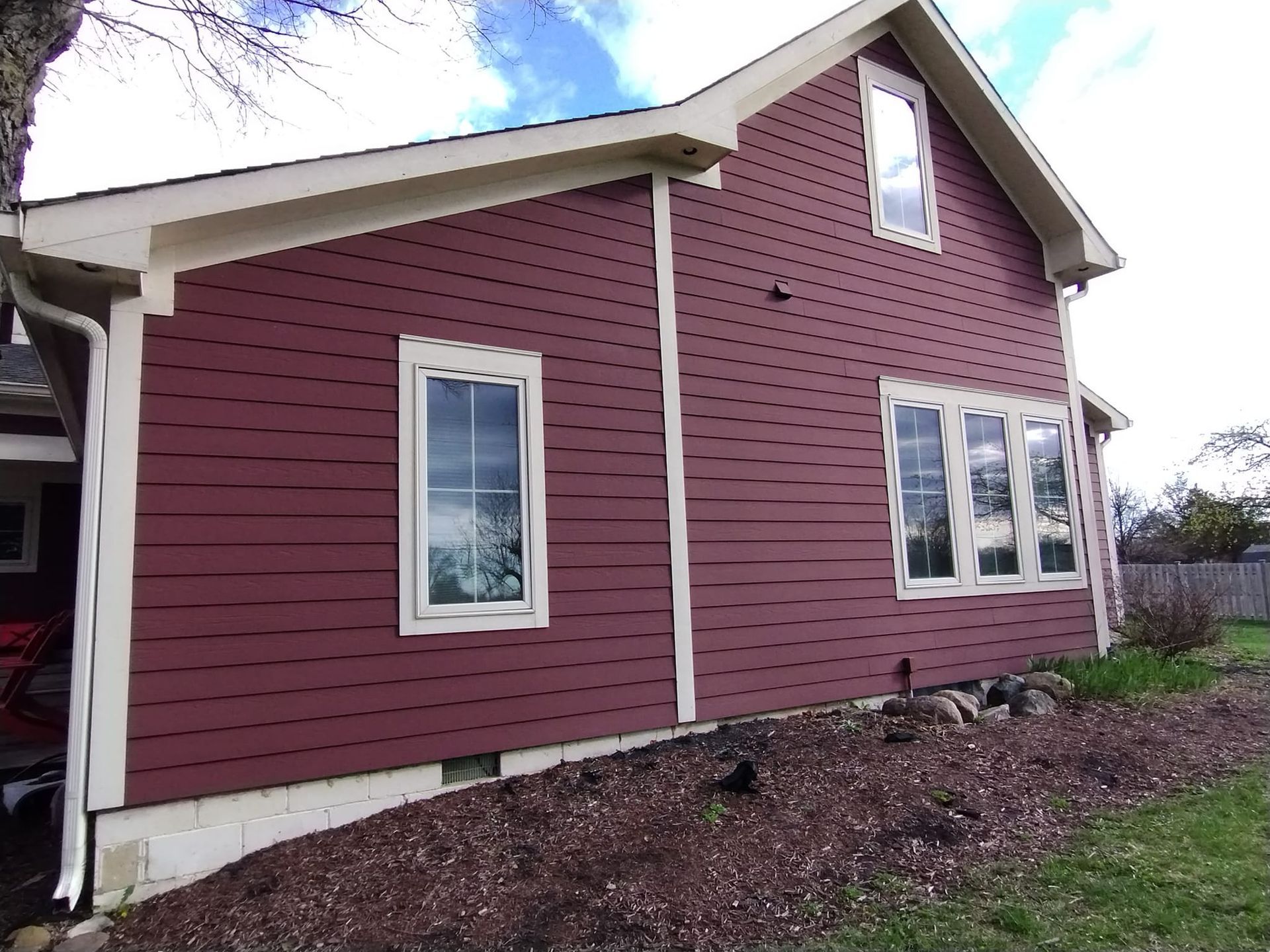 The side of a red house with a lot of windows.