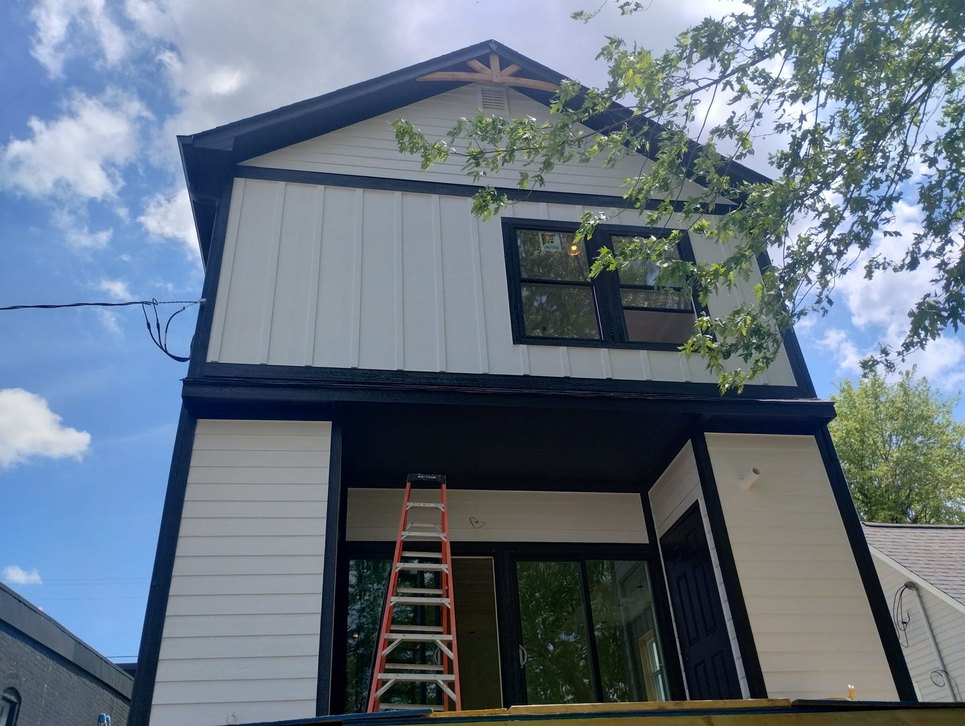 A white and black house with a ladder in front of it.
