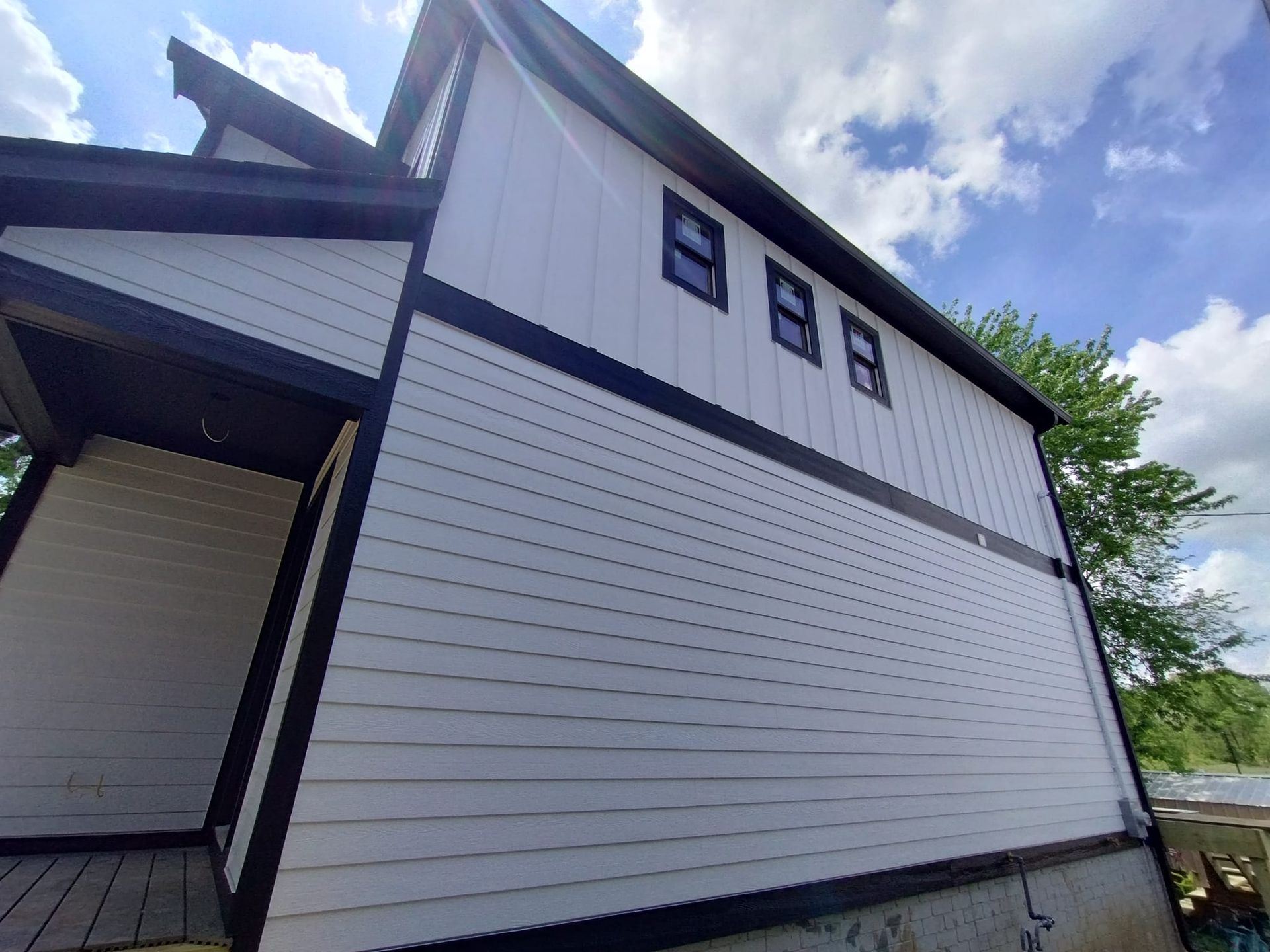 A white house with black trim and a blue sky in the background