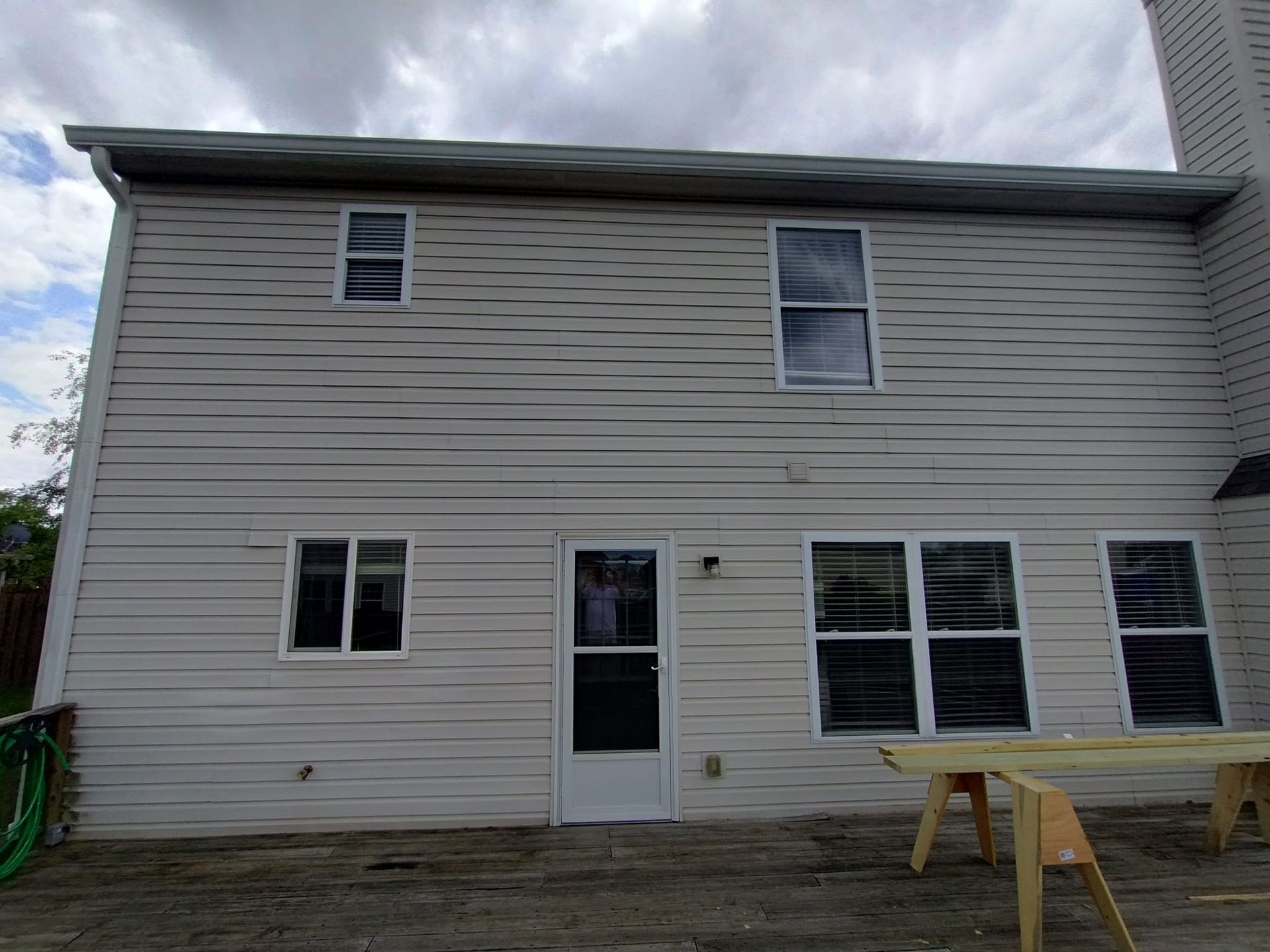 The back of a house with a wooden table in front of it.