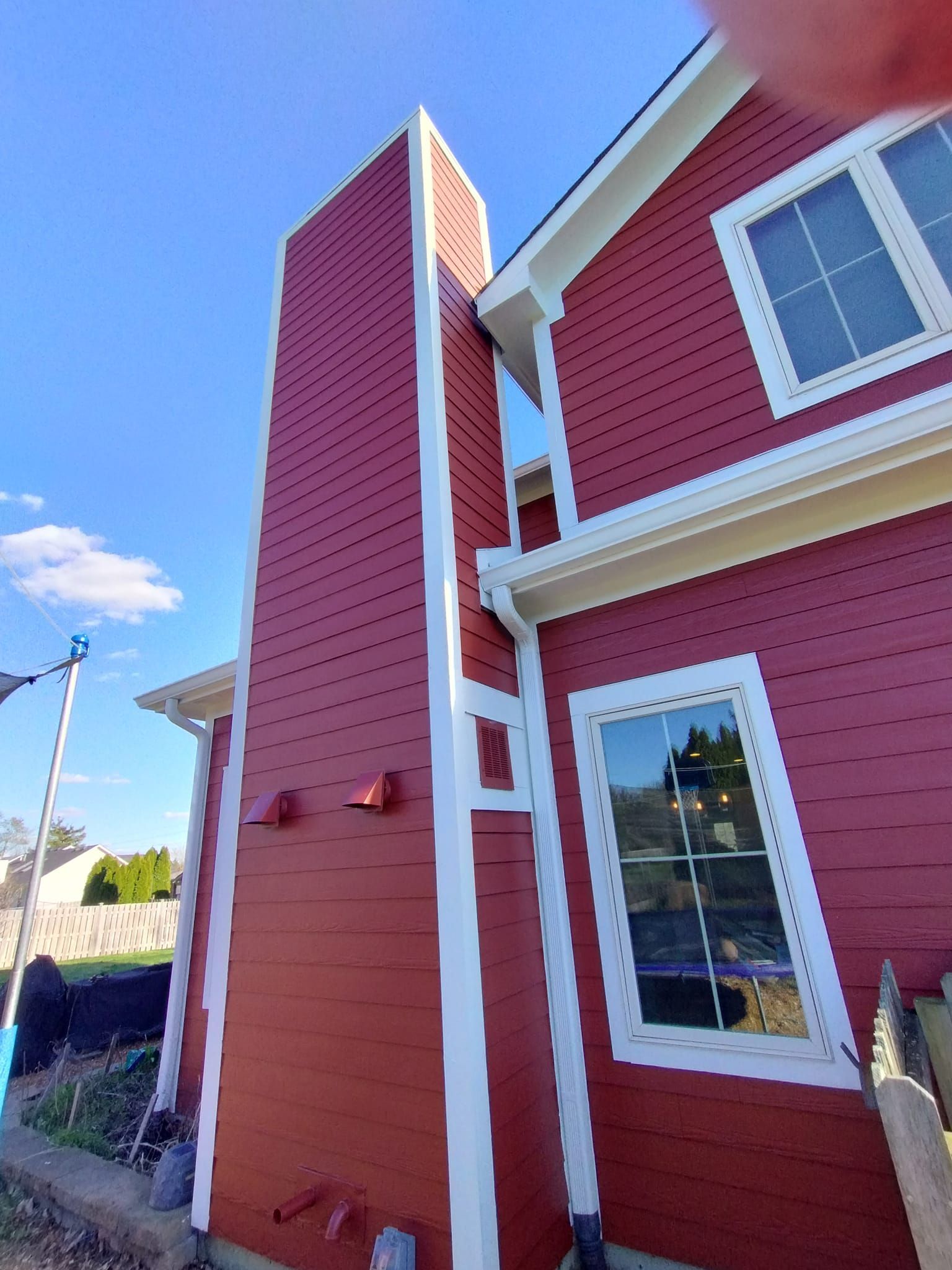 A red house with white trim and a chimney on the side