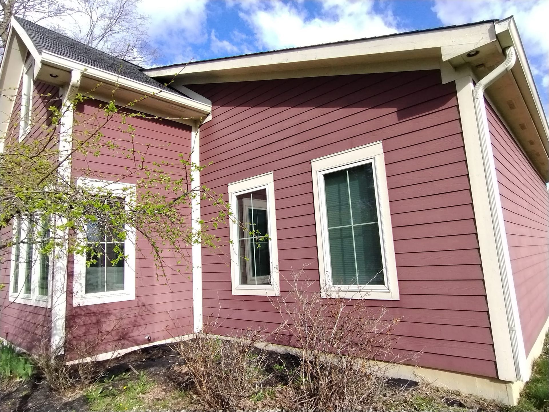 A red house with white trim and windows on a sunny day.