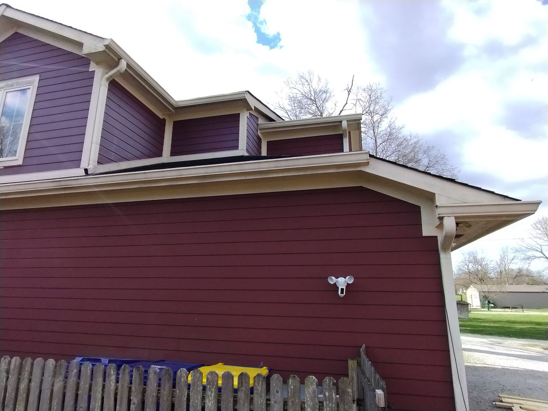 A red house with a wooden fence in front of it.