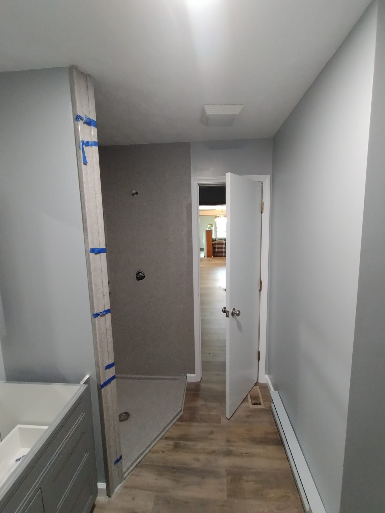 A hallway leading to a bathroom with a shower and a sink.