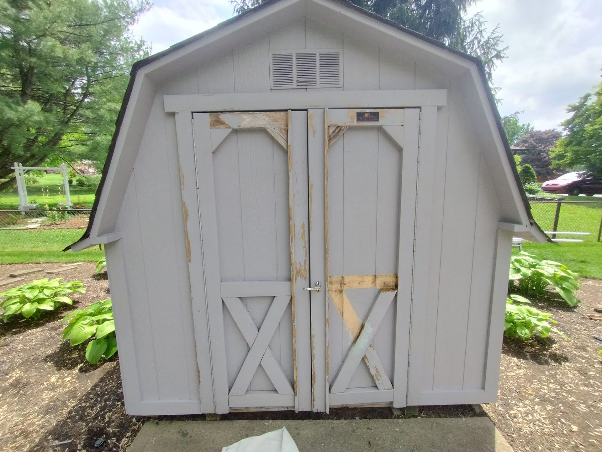 A white barn shed with a black roof