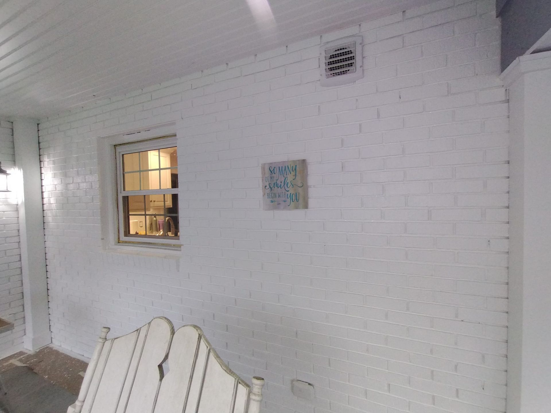 A white brick wall with a window and a clock on it