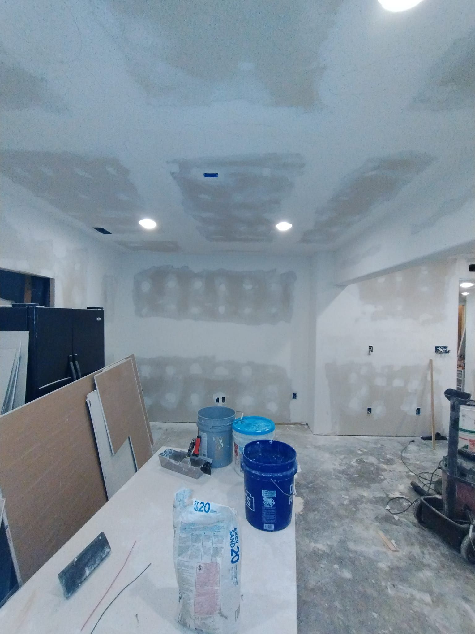 A room that is being remodeled with buckets on a table.