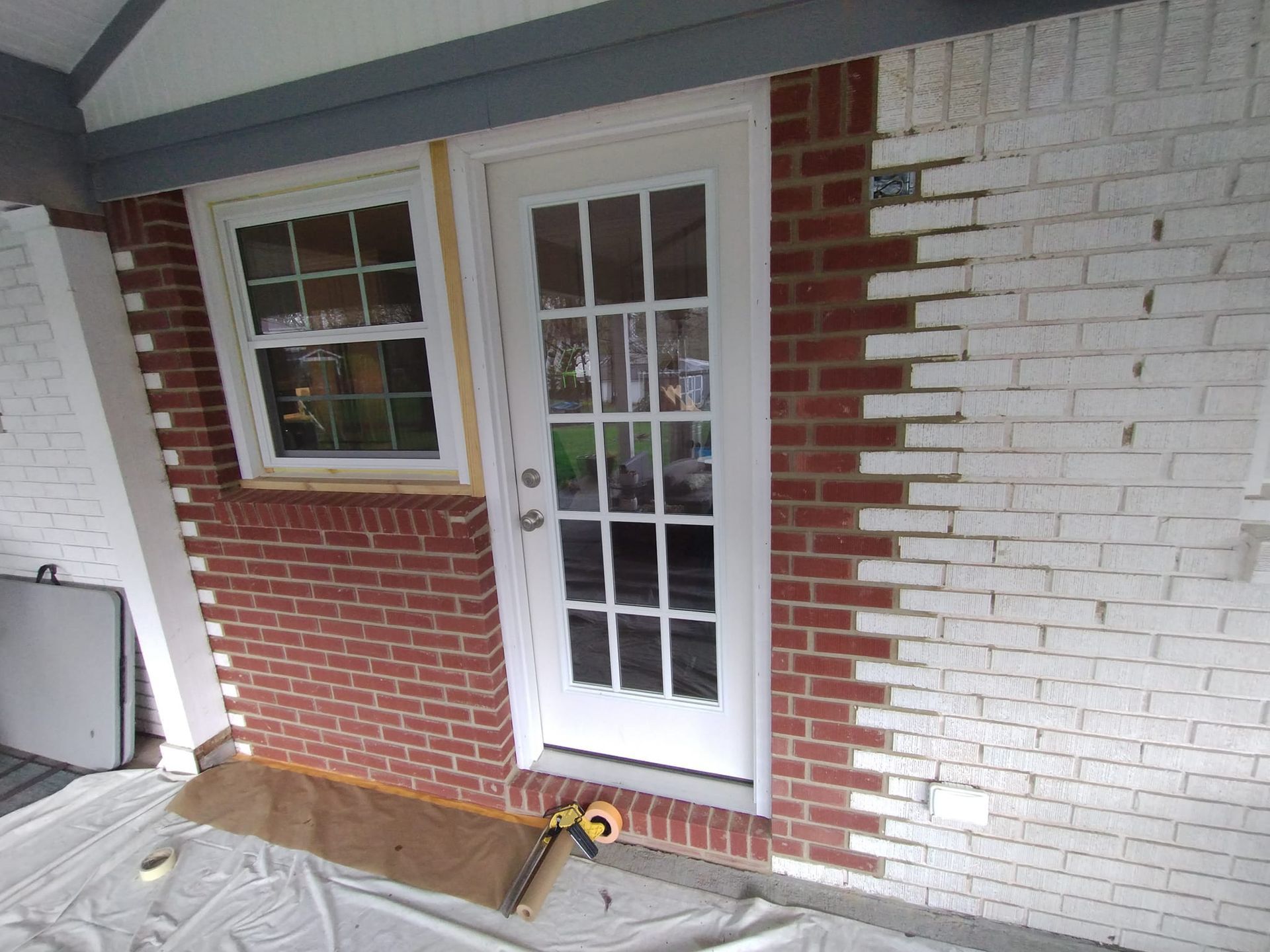 A white door is being painted on a brick wall