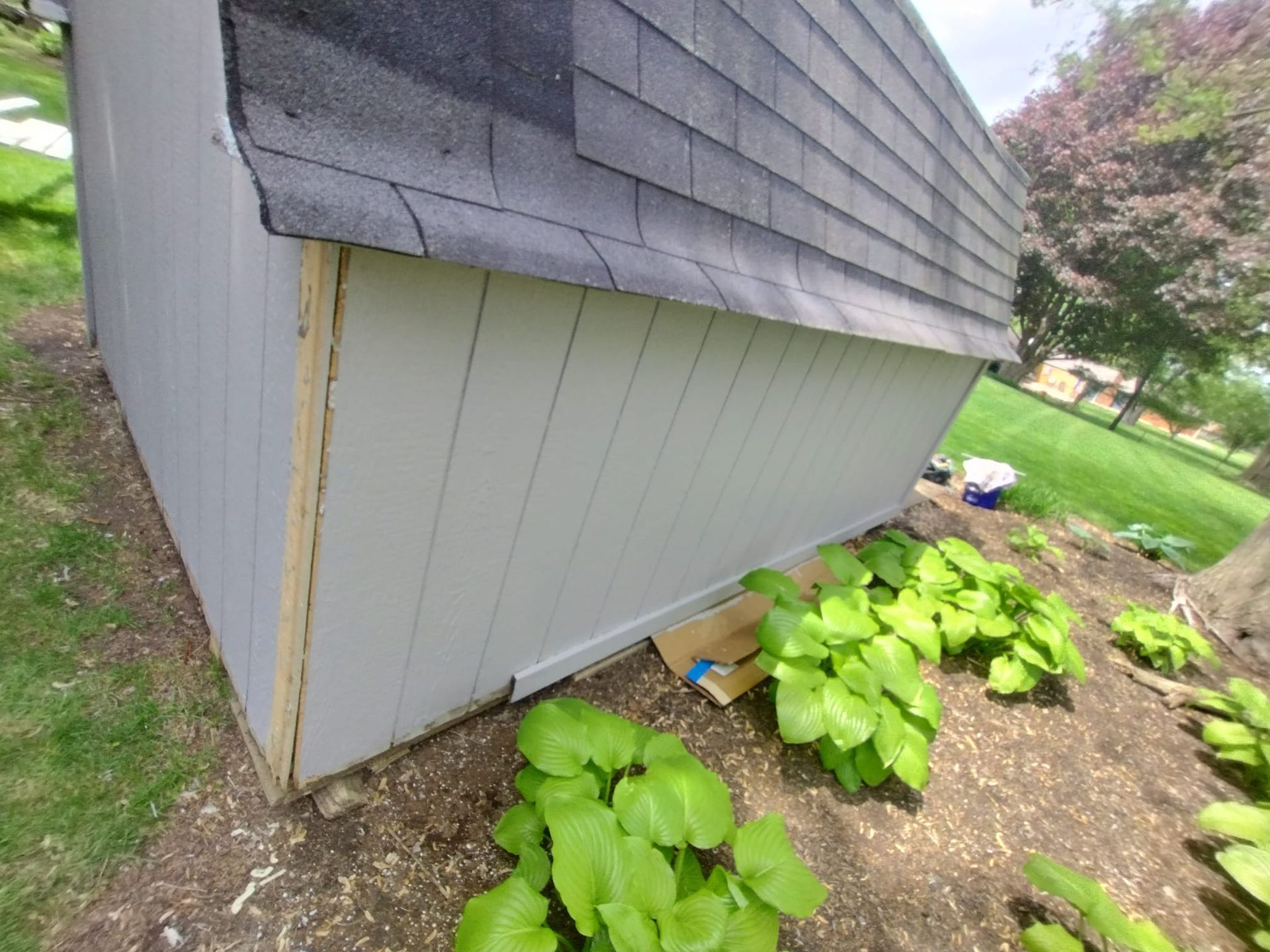 A shed with a roof is sitting in the middle of a garden.