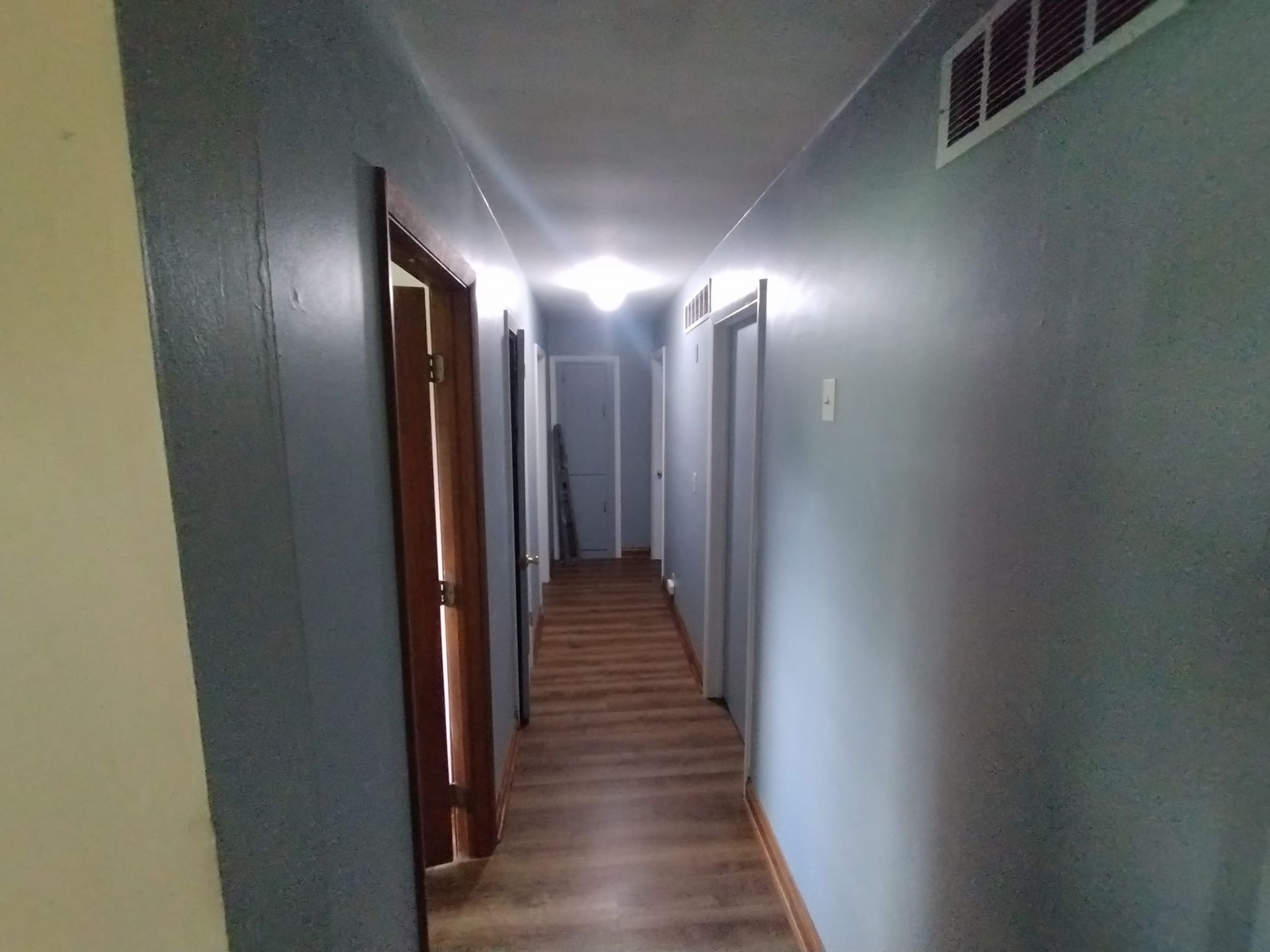 A long hallway with wooden floors and blue walls.