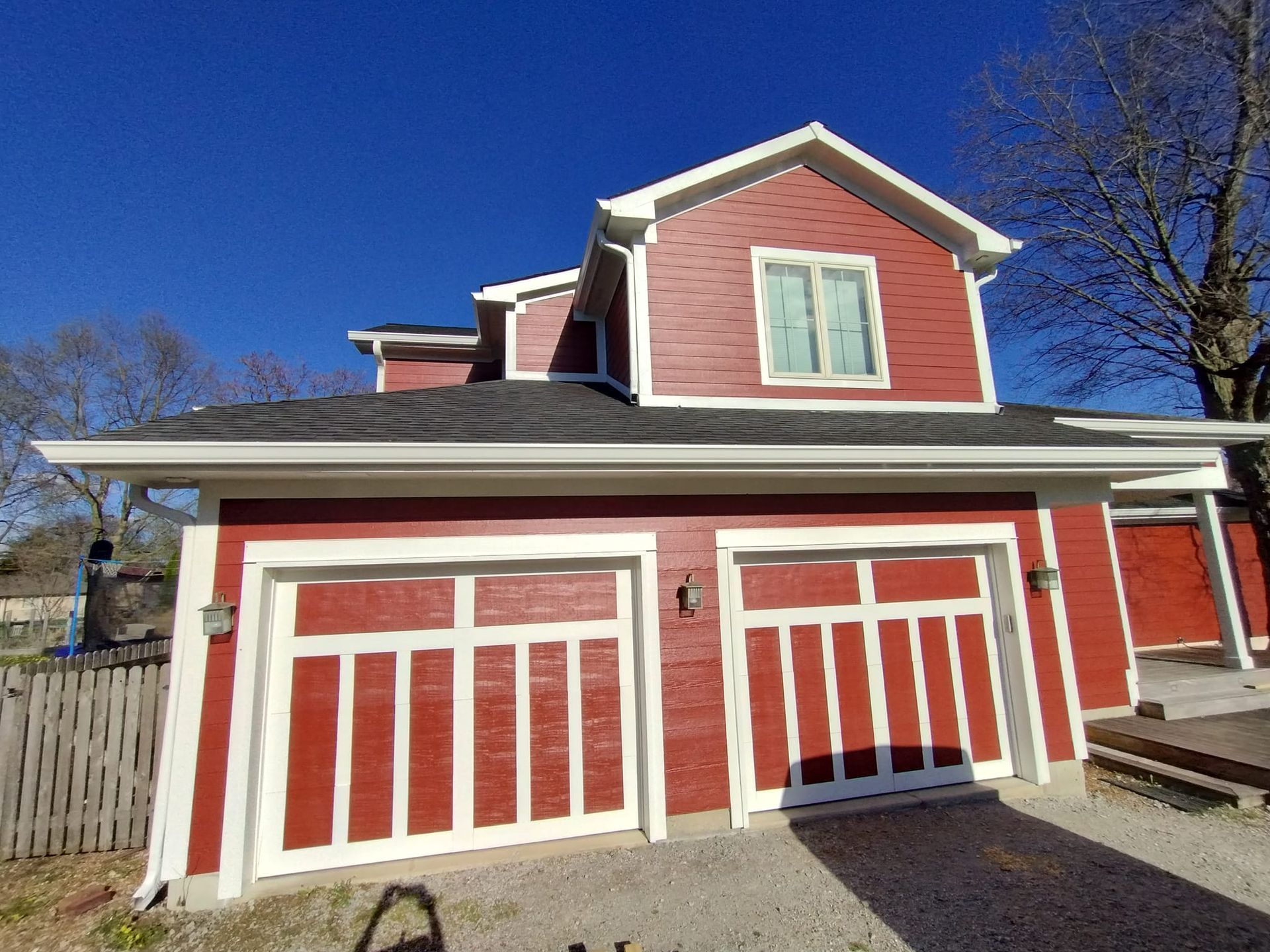 A red house with two garage doors and a blue sky in the background