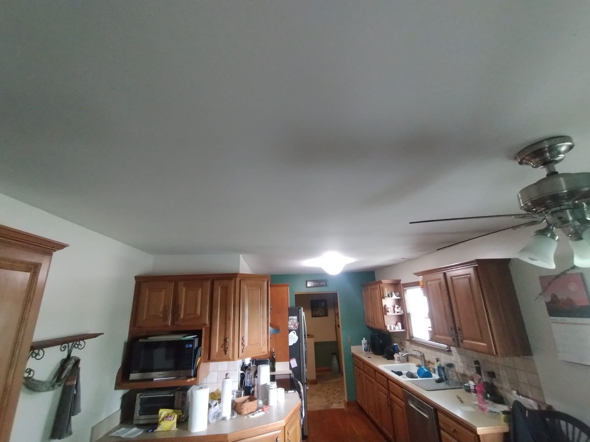 A kitchen with wooden cabinets and a ceiling fan