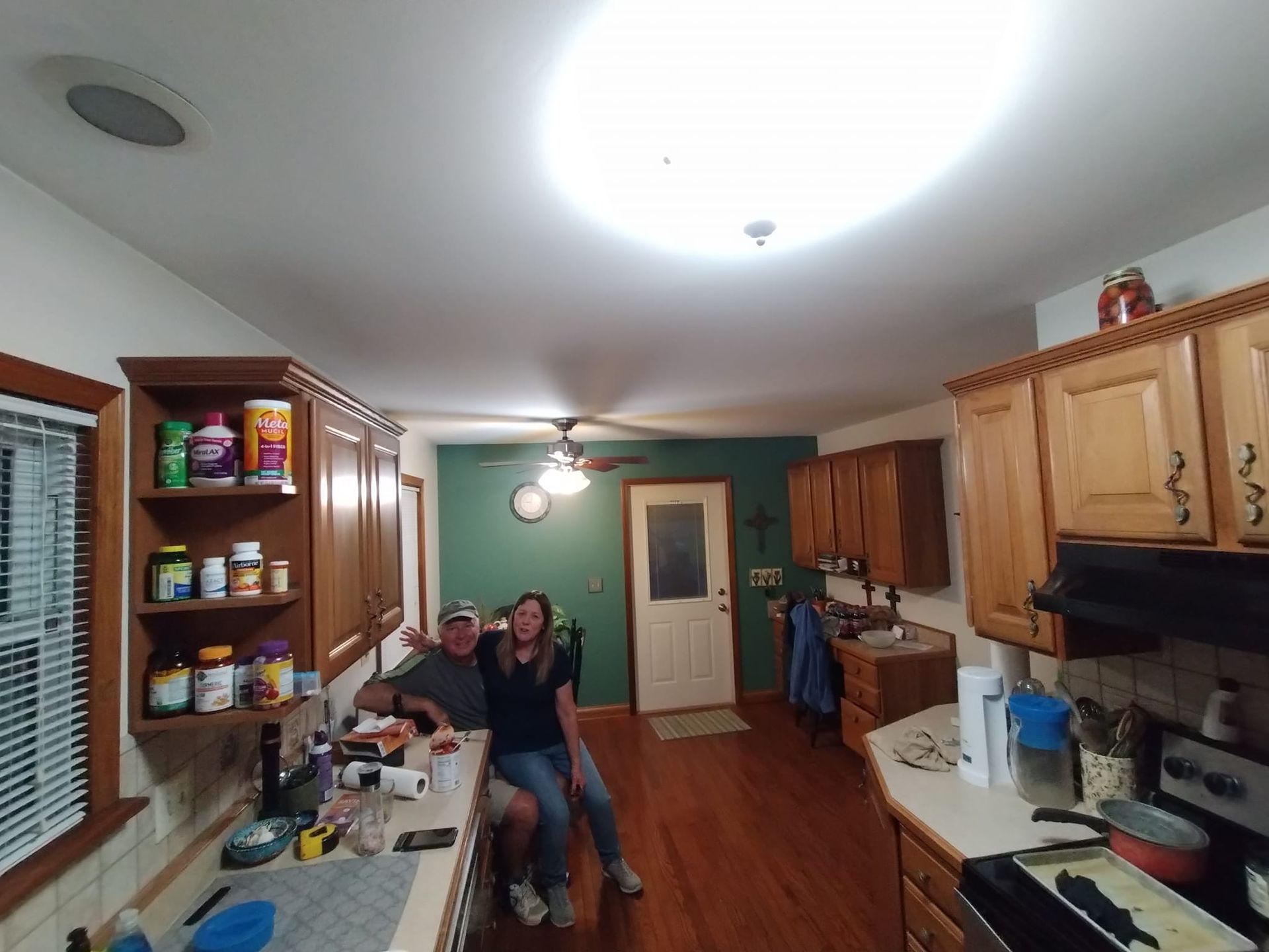 A man and a woman are posing for a picture in a kitchen.