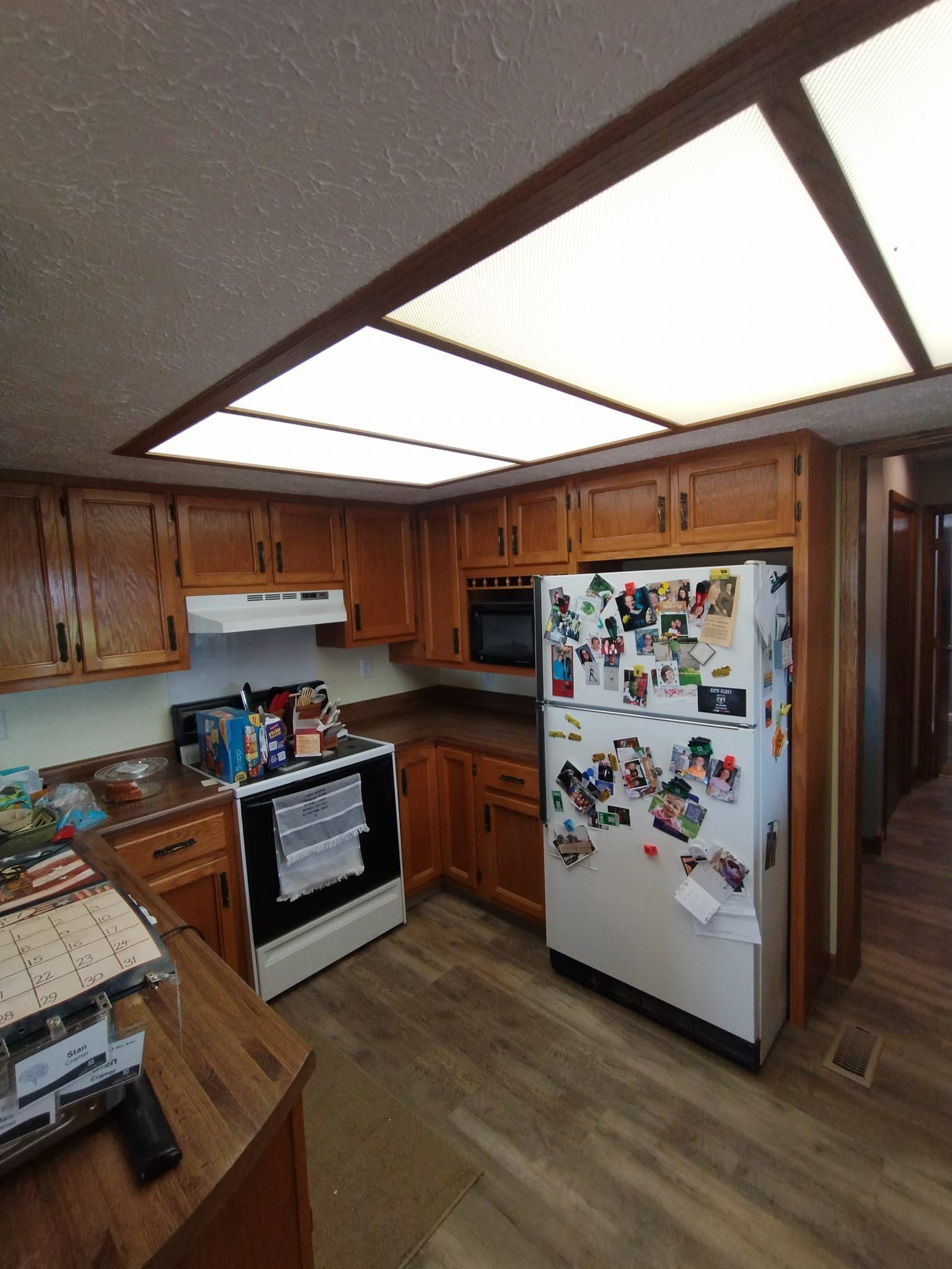 A kitchen with wooden cabinets , a refrigerator , stove and microwave.