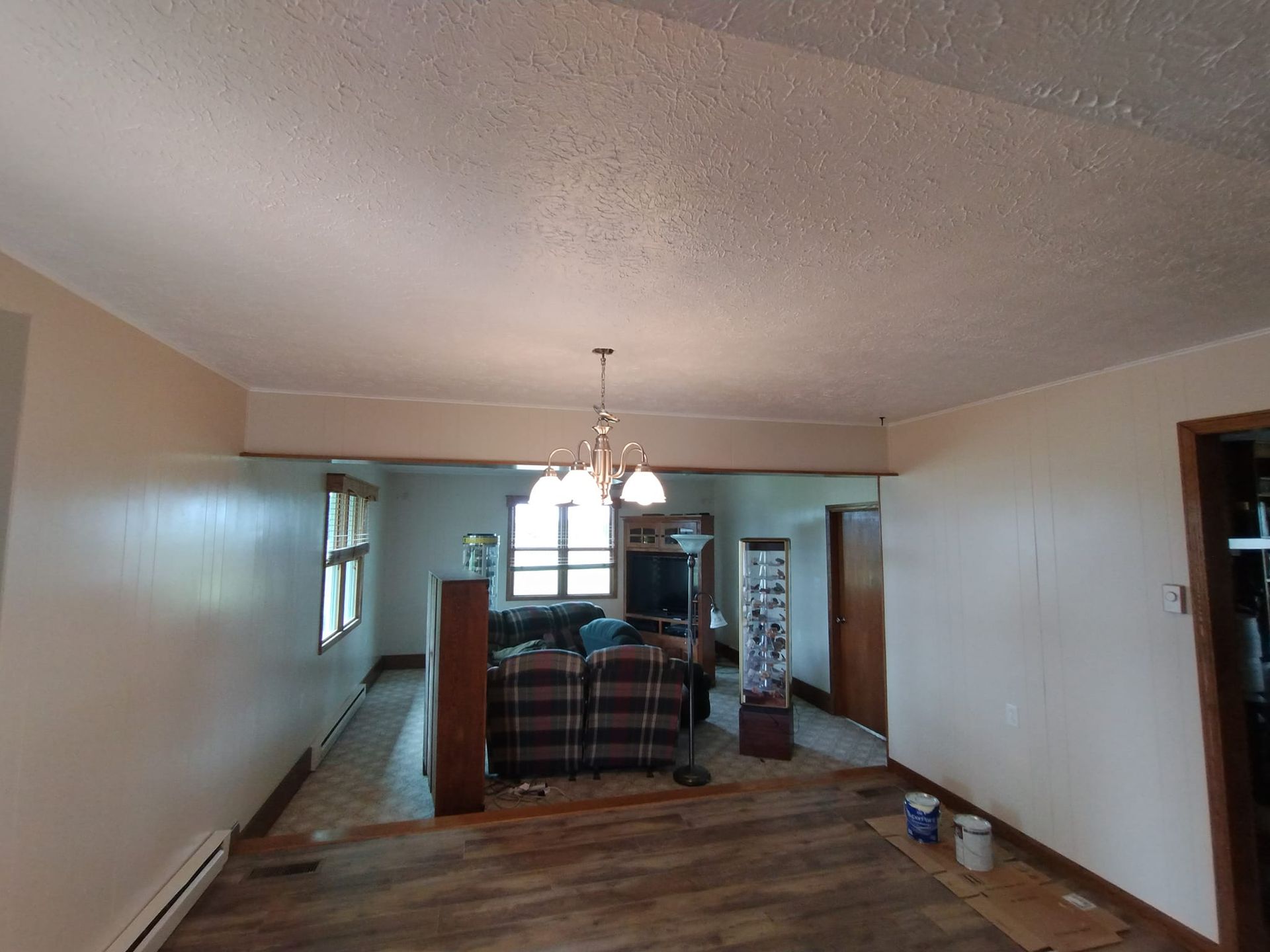 A living room with a couch and chairs and a chandelier hanging from the ceiling.