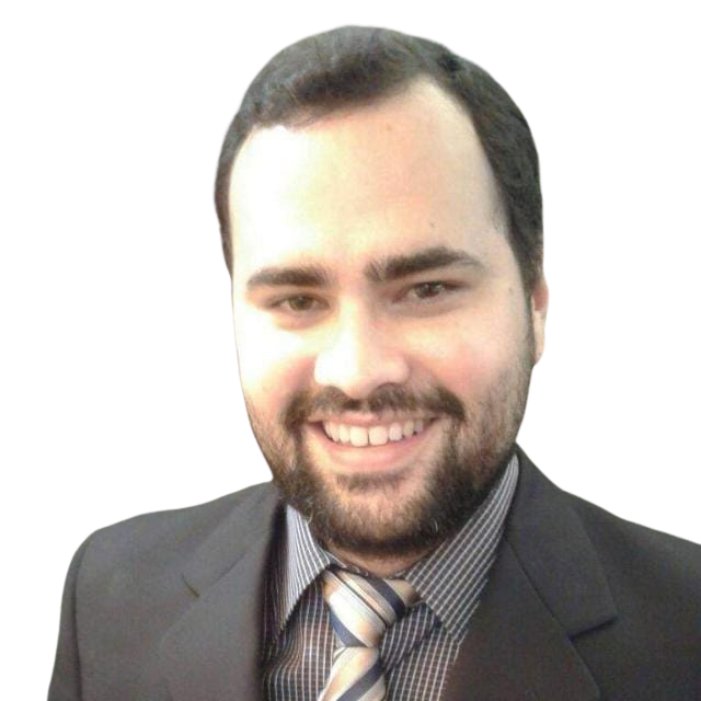 Homem de terno, sorrindo e com barba, em frente a um fundo branco.