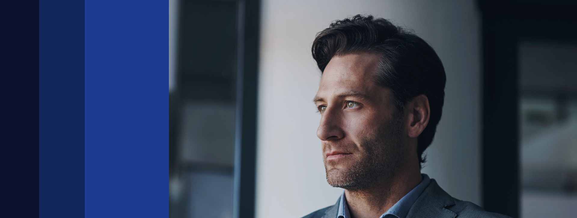 Homem de terno olhando pela janela, simbolizando visão estratégica e gestão de investimentos.