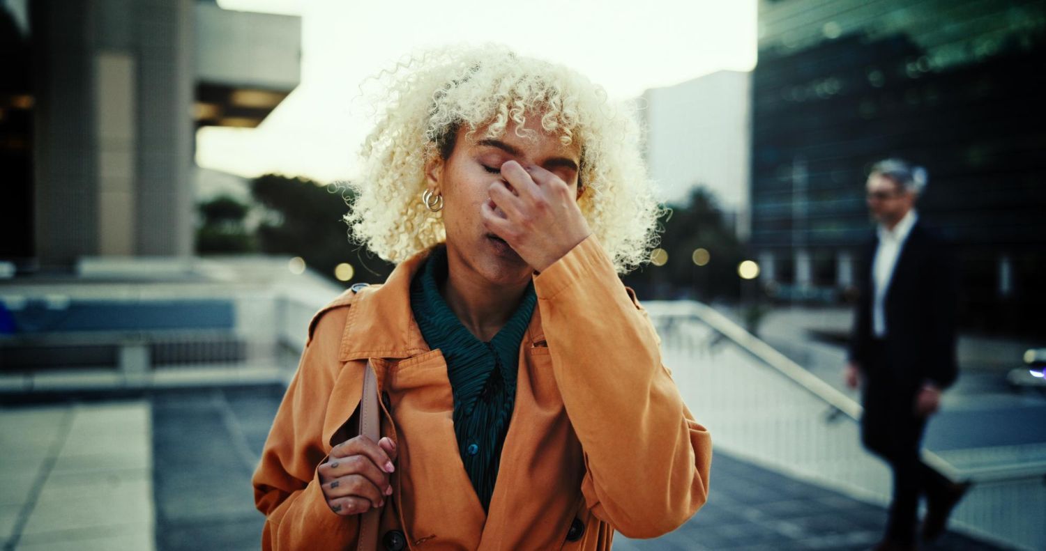 Elderly couple smiles while looking at a laptop on a couch. Woman has arm around man.