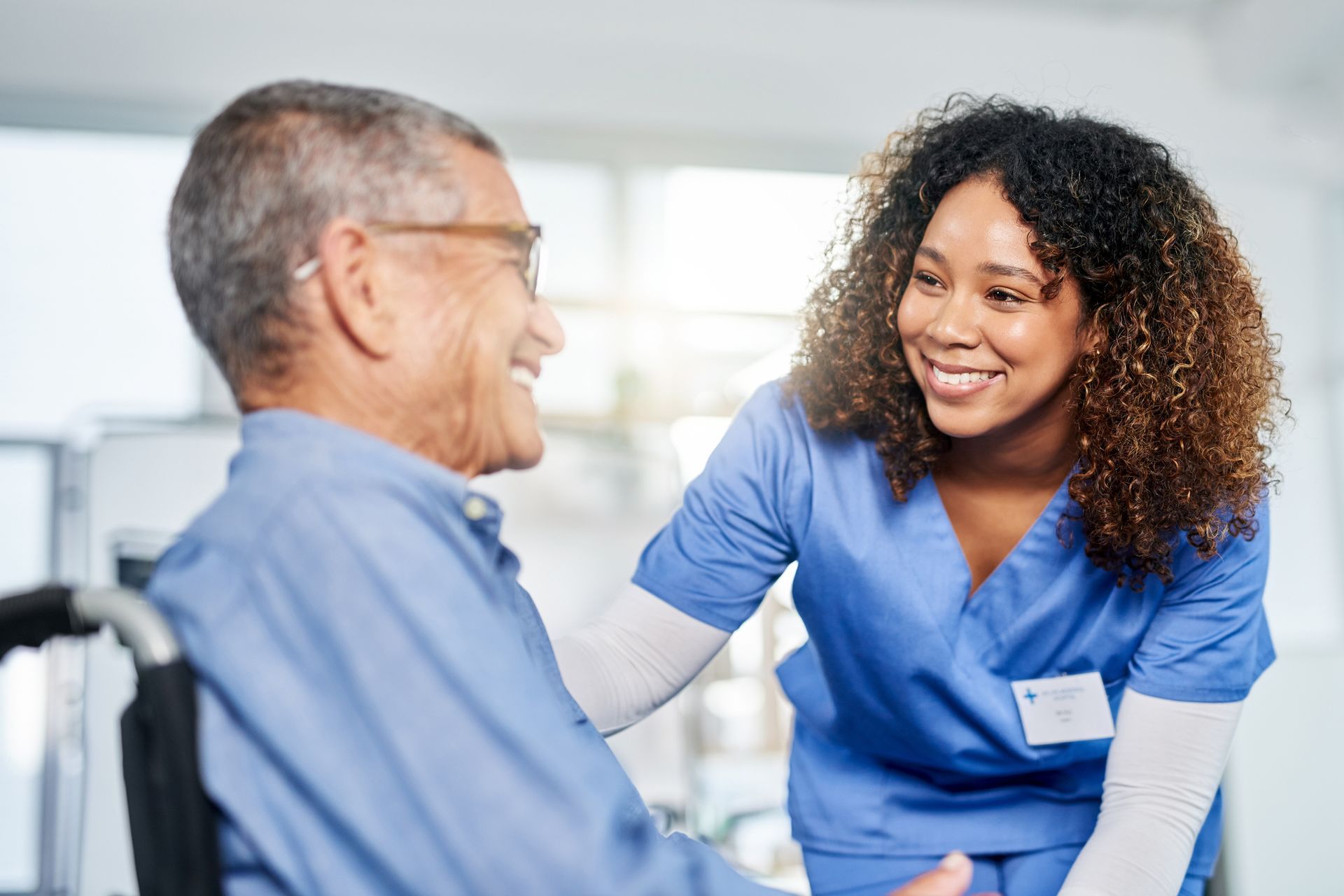 A nurse is talking to an elderly man in a wheelchair.