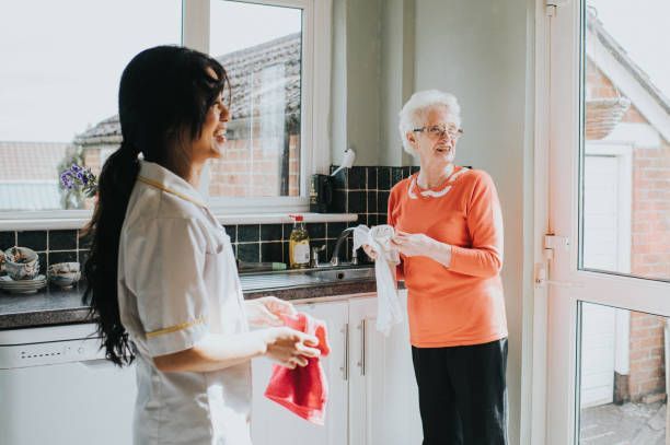 A nurse is talking to an elderly woman in a kitchen.