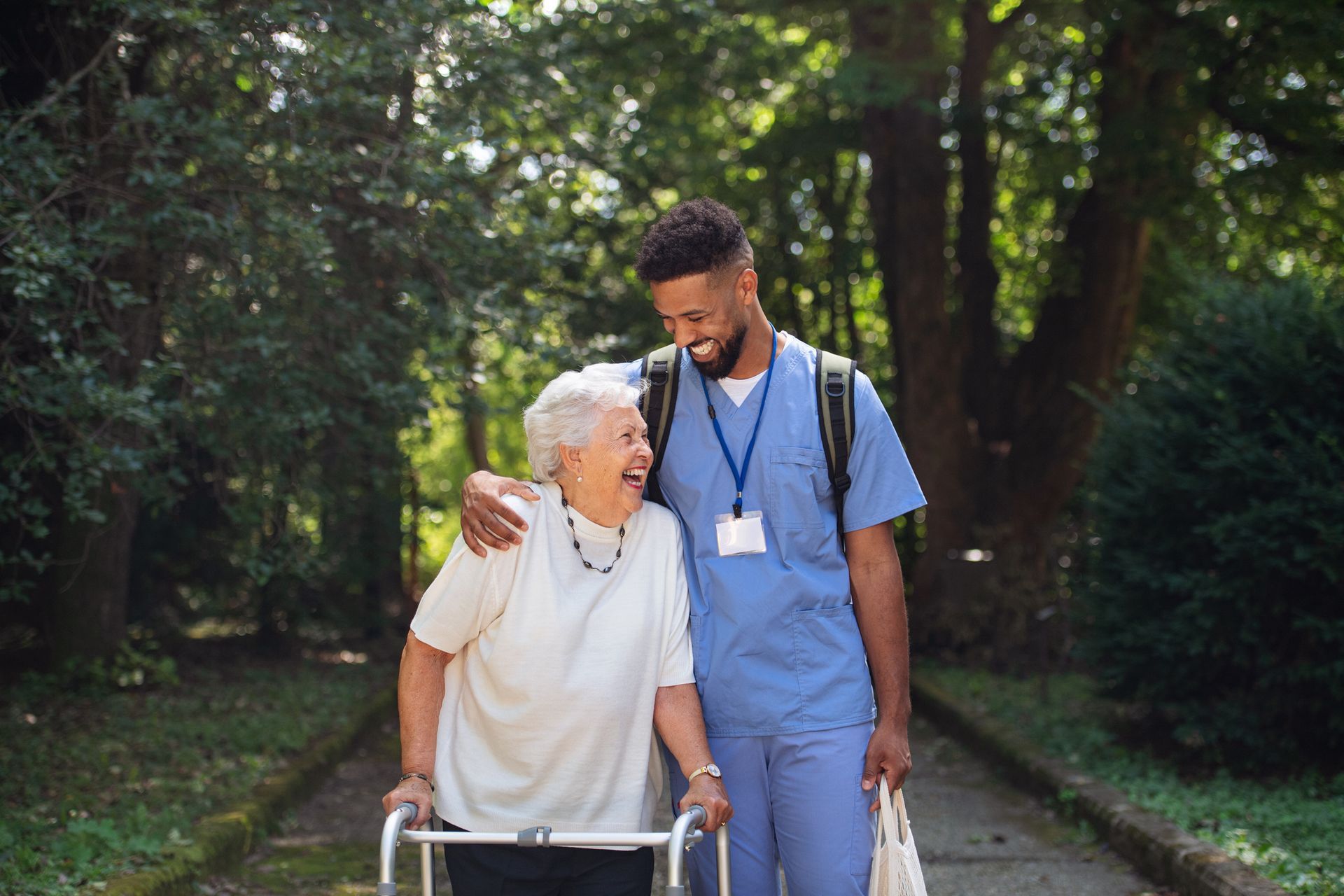 A nurse is helping an elderly woman with a walker.