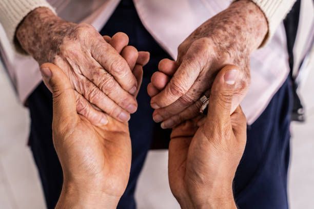 A man is holding the hands of an elderly woman.