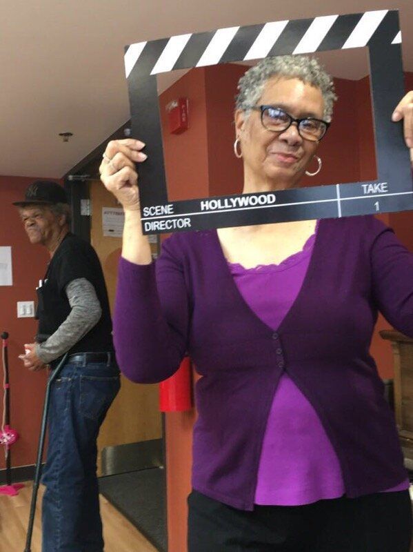 An elderly woman striking a pose in front of a camera.