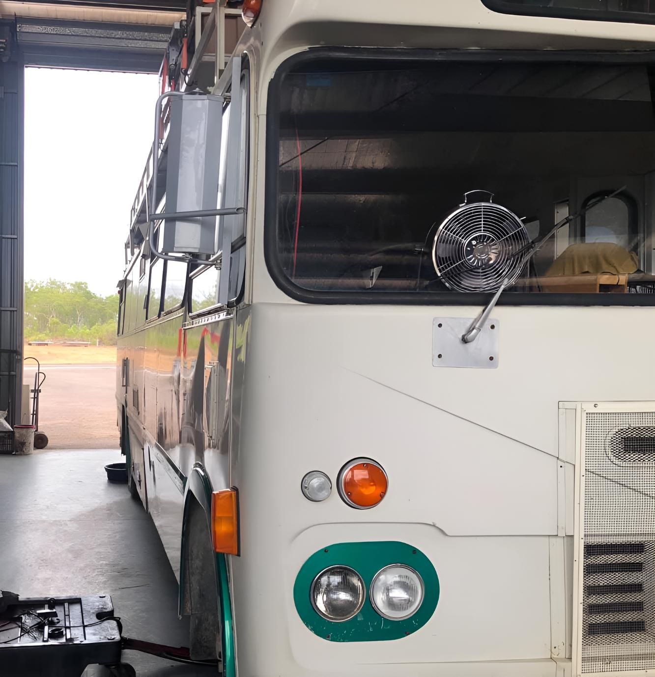 A White Bus is Parked in a Garage With the Door Open — All things Diesel NT in Tivendale, NT