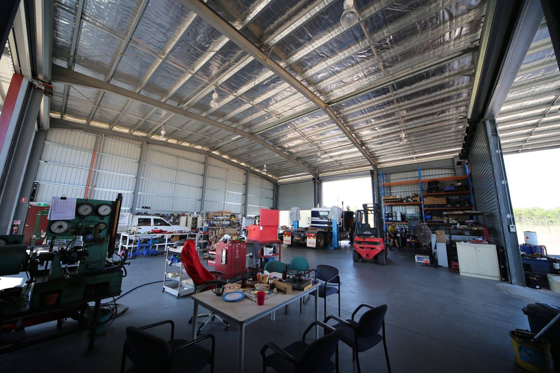 A large mechanics workshop with a table and chairs and a truck parked inside — All things Diesel NT in Coolalinga, NT 