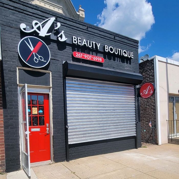 A's Beauty Boutique storefront featuring a black brick exterior, a red door, and a metal security gate.