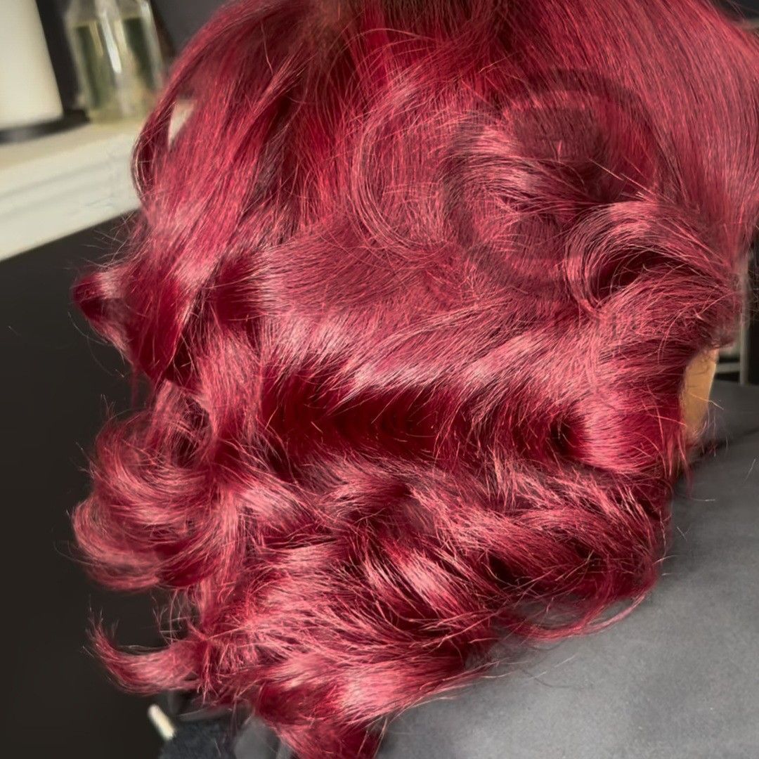Back view of shoulder-length, deep red hair styled in loose, soft curls with a glossy finish.