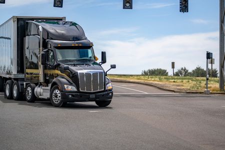 A semi truck is driving down a highway at an intersection.