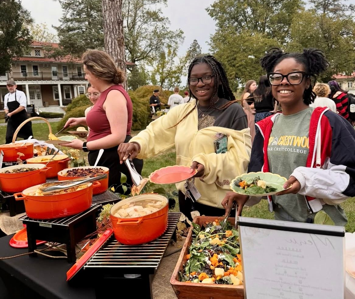 People serving food from serving dishes at an outdoor event.