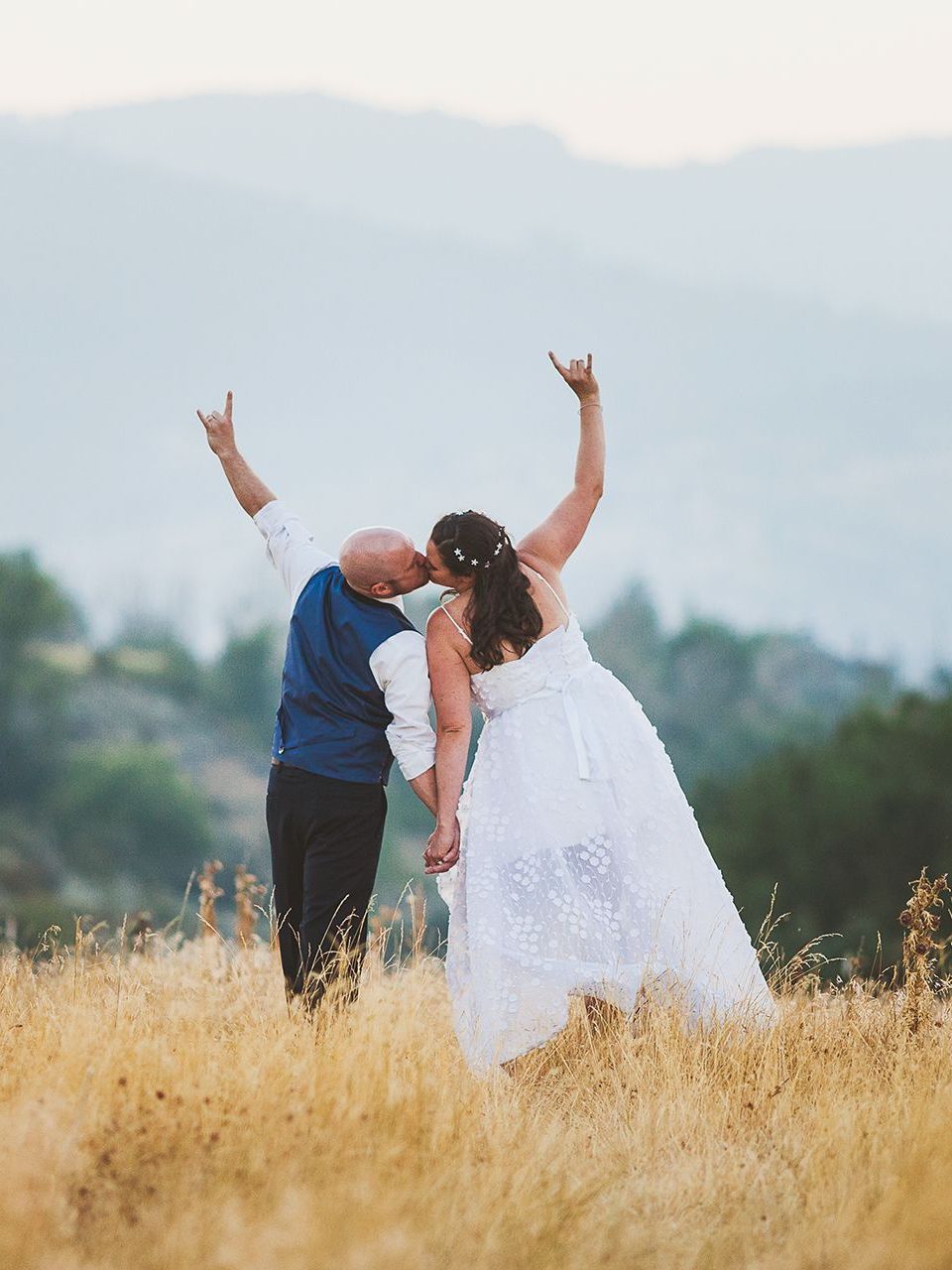 A bride and groom are kissing in a field of tall grass.