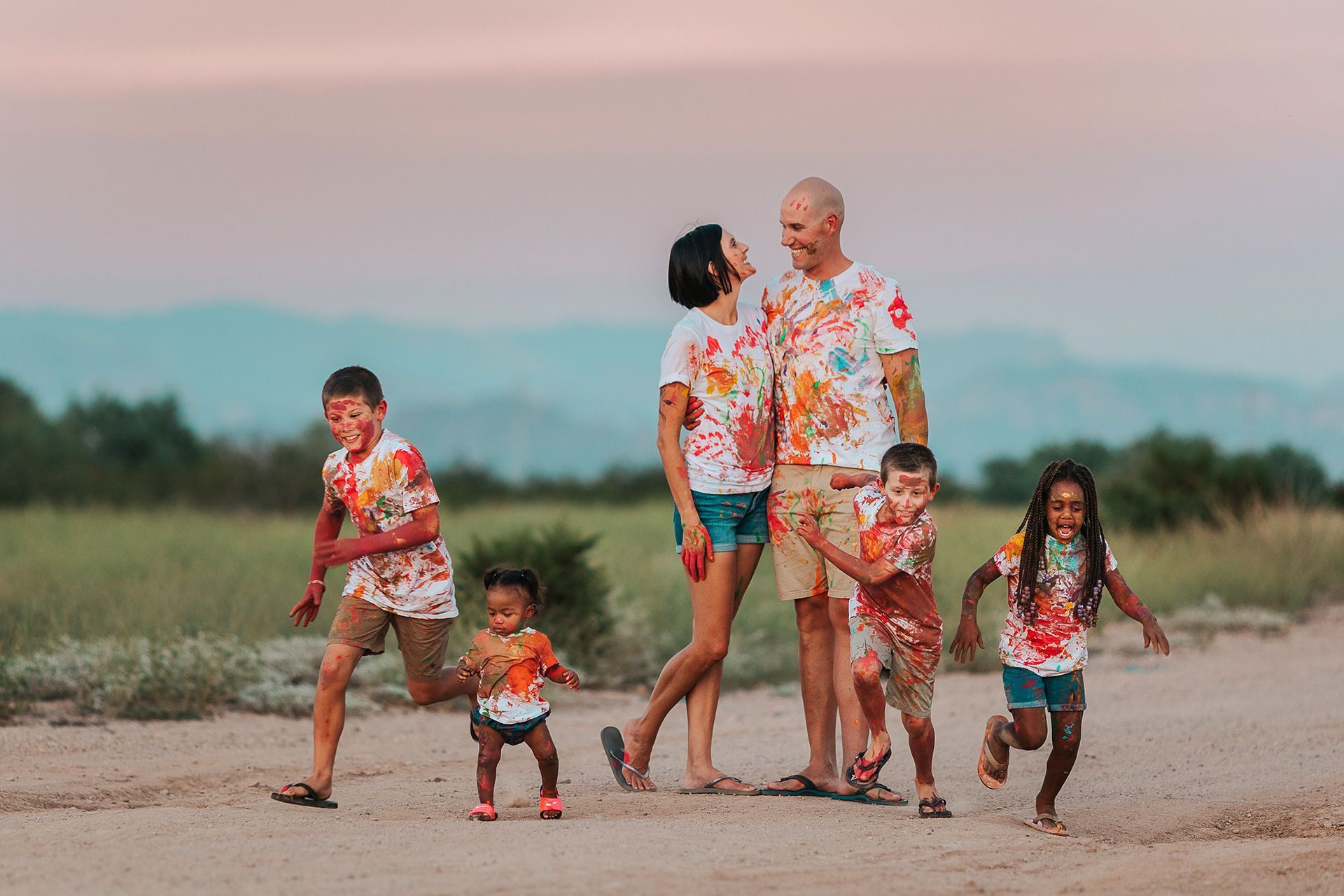 A family is playing with colored powder on a dirt road.