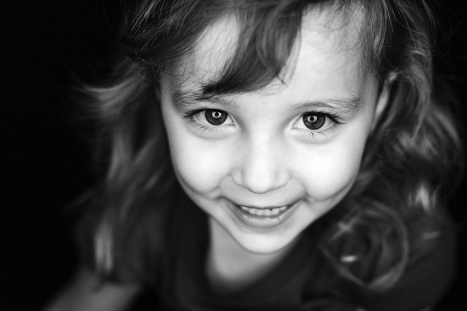 A little girl is smiling in a black and white photo.