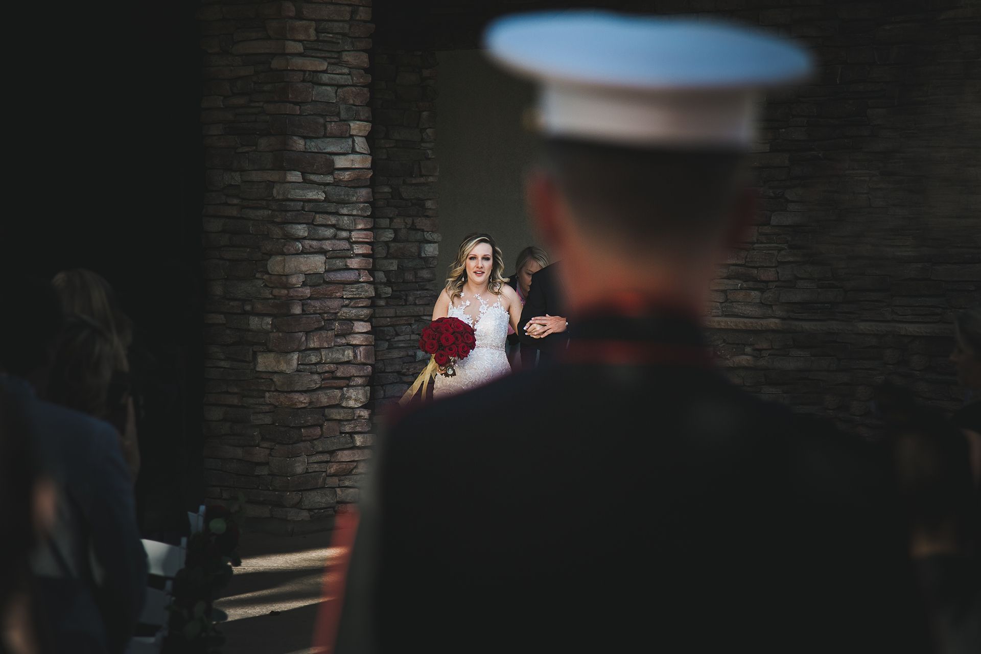 A bride is walking down the aisle while a man in a military uniform watches.