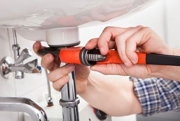 a plumber is fixing a sink with a wrench