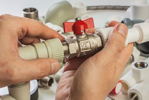 a person is fixing a water valve on a pipe