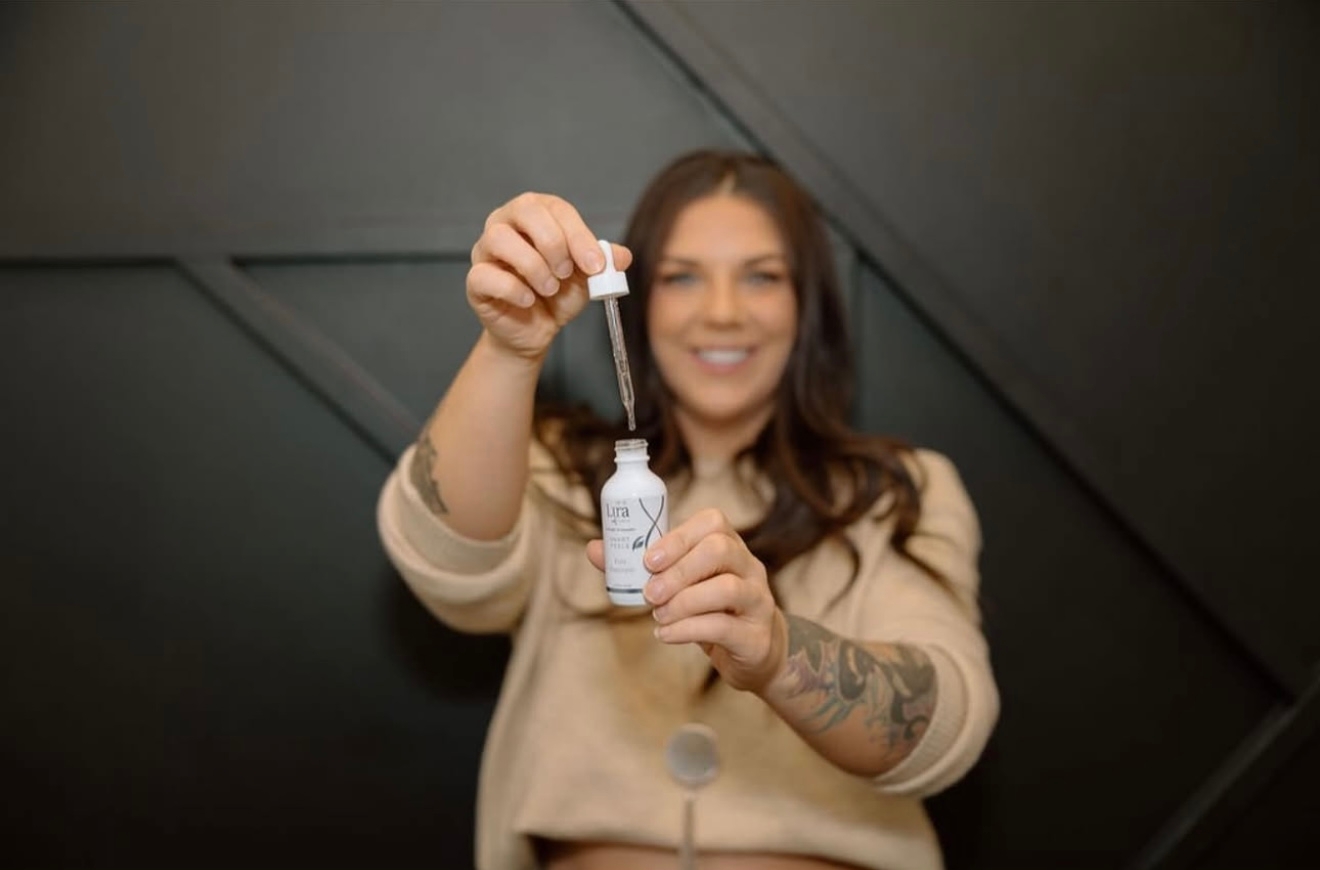A woman is holding a bottle with a dropper in her hand.