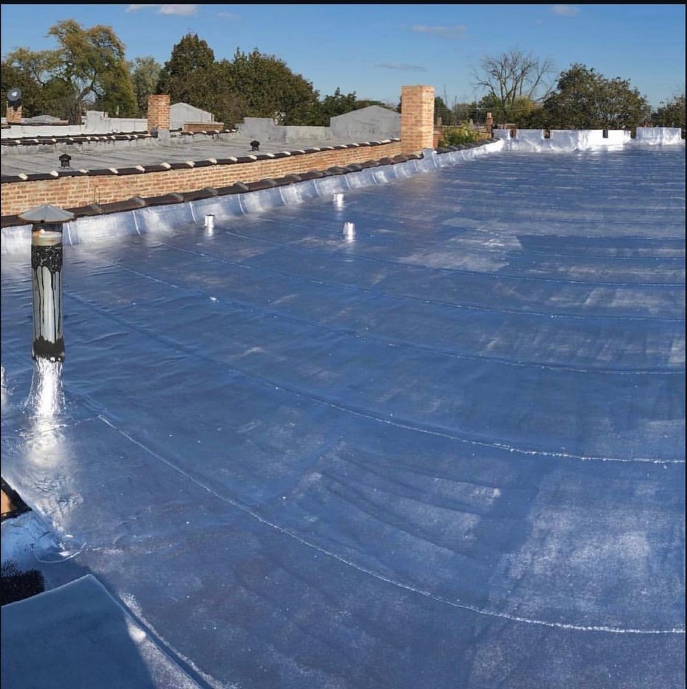 Blue roofing membrane on a flat roof with brick perimeter and vents under a blue sky.